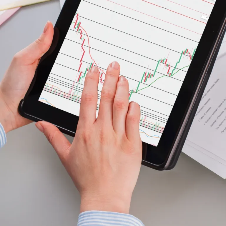 Mains posées sur une tablette affichant un graphique de cours en hausse et en baisse