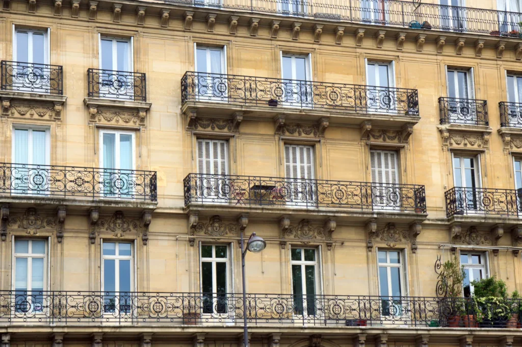 Façade d’immeuble haussmannien en pierre avec balcons en fer forgé à Paris