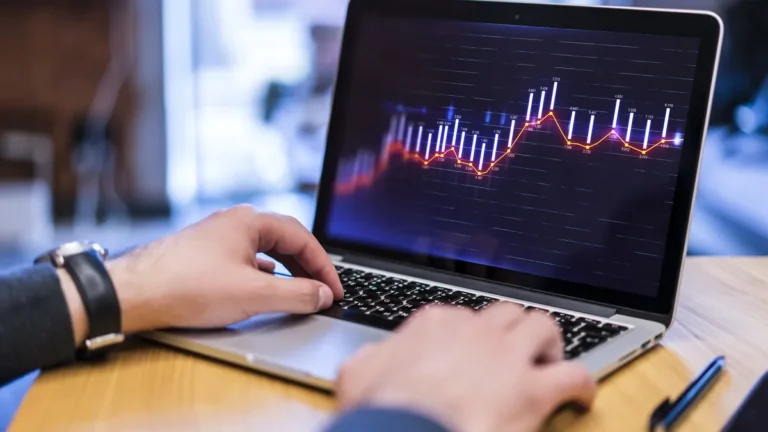 Mains sur le clavier d’un ordinateur portable affichant un graphique boursier
